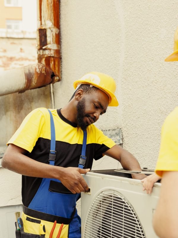 Competent mechanic and expert repairman disassembling old broken air conditioner to replace it with new performant outdoor hvac system after draining refrigerant and replacing ductwork